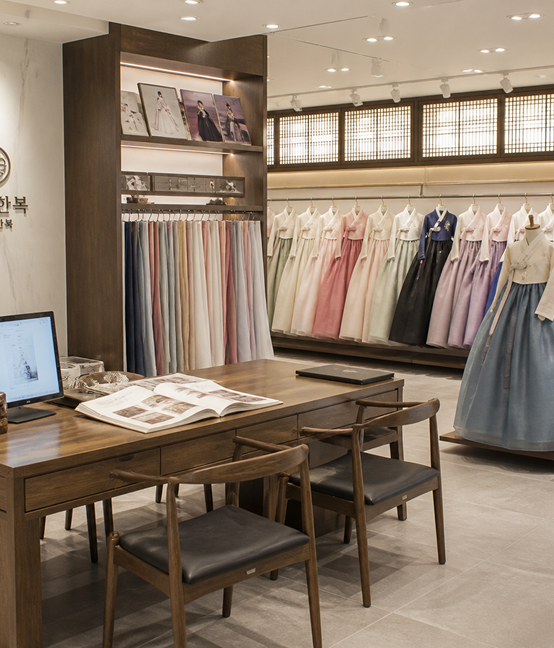 A tailor's atelier lined with fabric bolts and a wooden work table