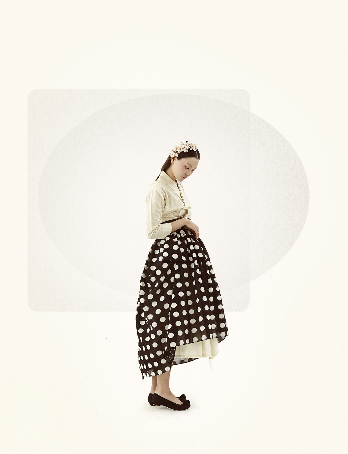 A model in a cream jacket and dotted full skirt