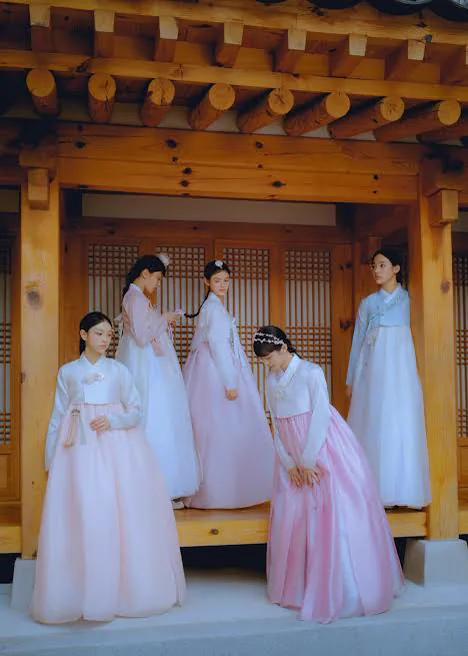 Five women wearing pastel hanbok on a wooden porch