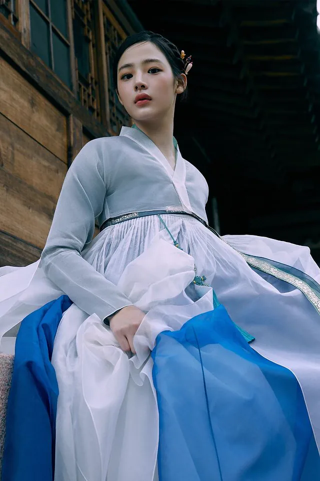 A woman wearing a blue and white hanbok outdoors