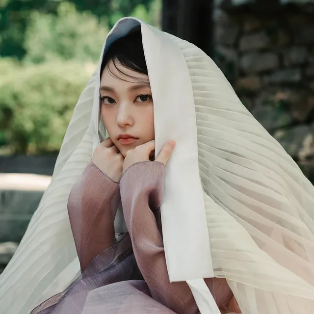 A woman framed by an ivory pleated veil
