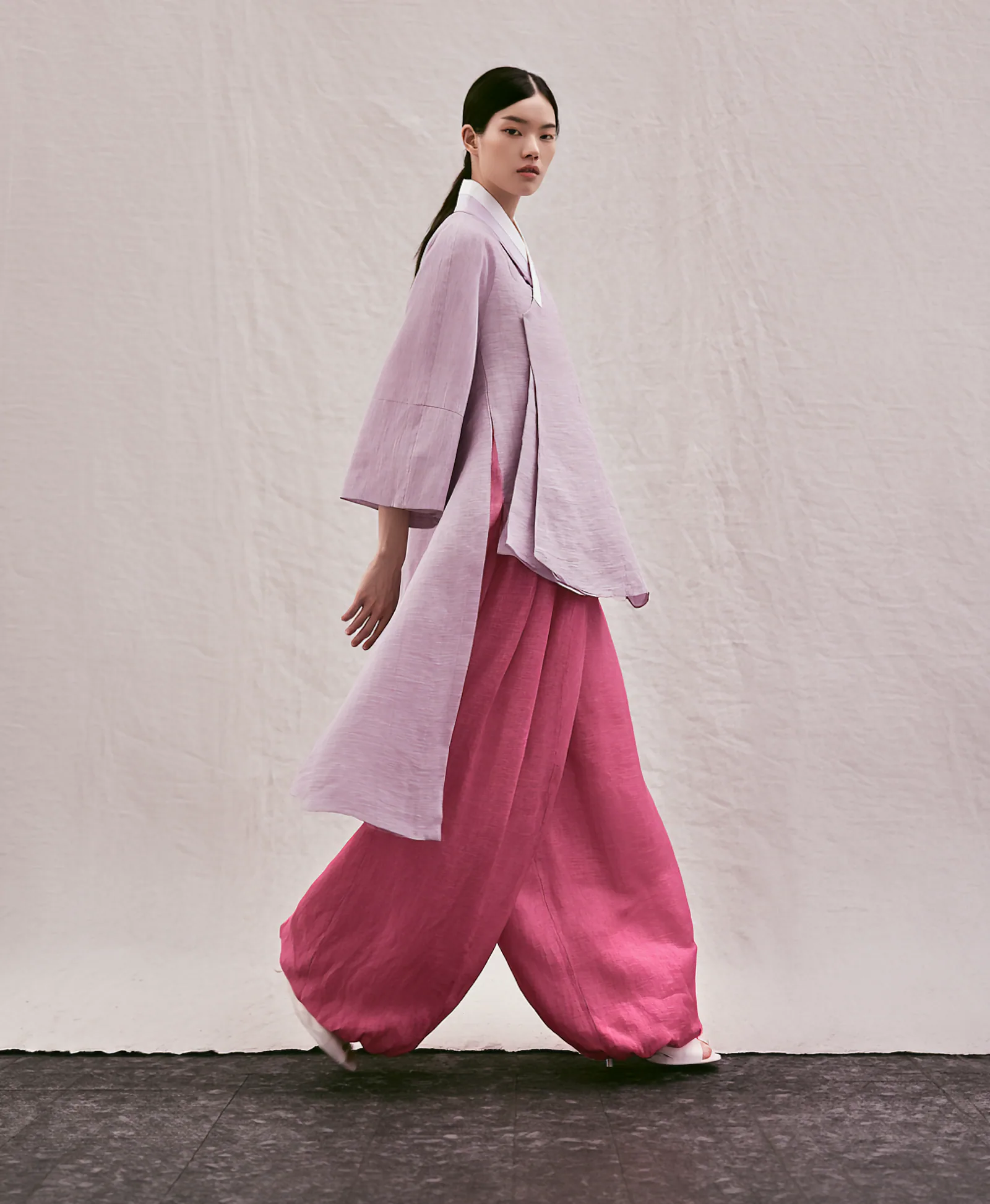 A model wearing the Git Baenaet Coat, an open-front linen coat with wide sleeves and long side slits
